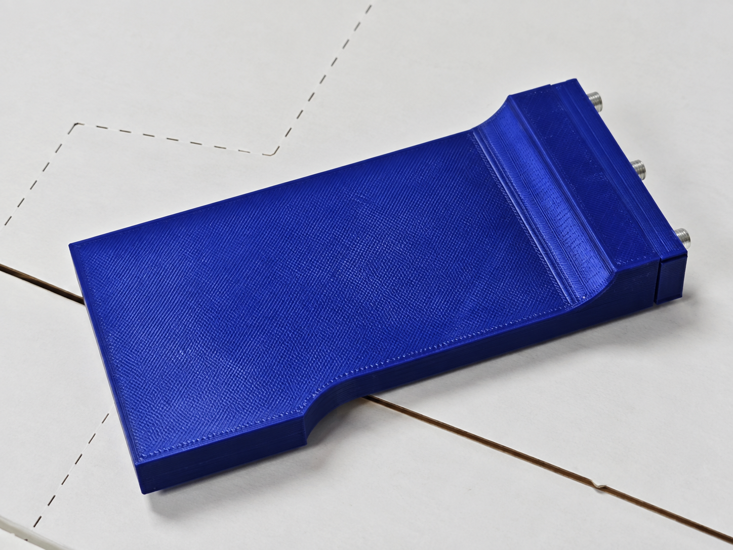 Blue 3D-printed PETG tool on a cardboard box, with a front plate and three screws